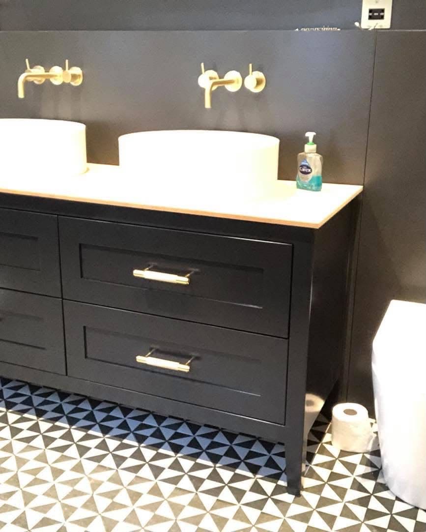 Black painted Shaker-style bathroom vanity with gold handles and double sinks