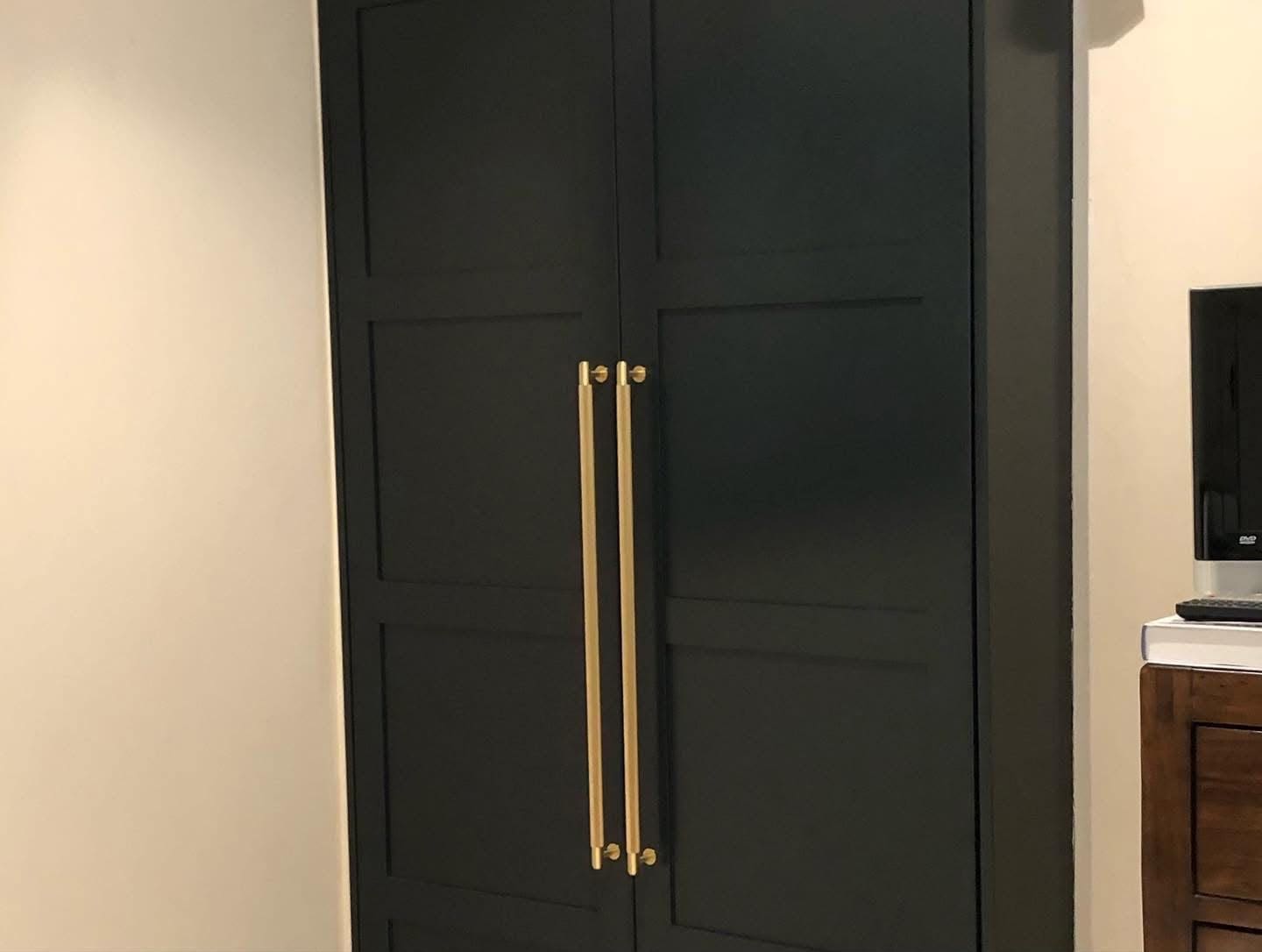 Black painted Shaker-style fitted wardrobe with long gold handles